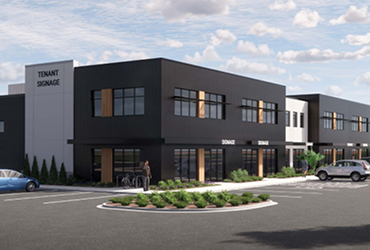 A two-story building with windows on both floors. A parking lot wraps around it with tenant signs visible.